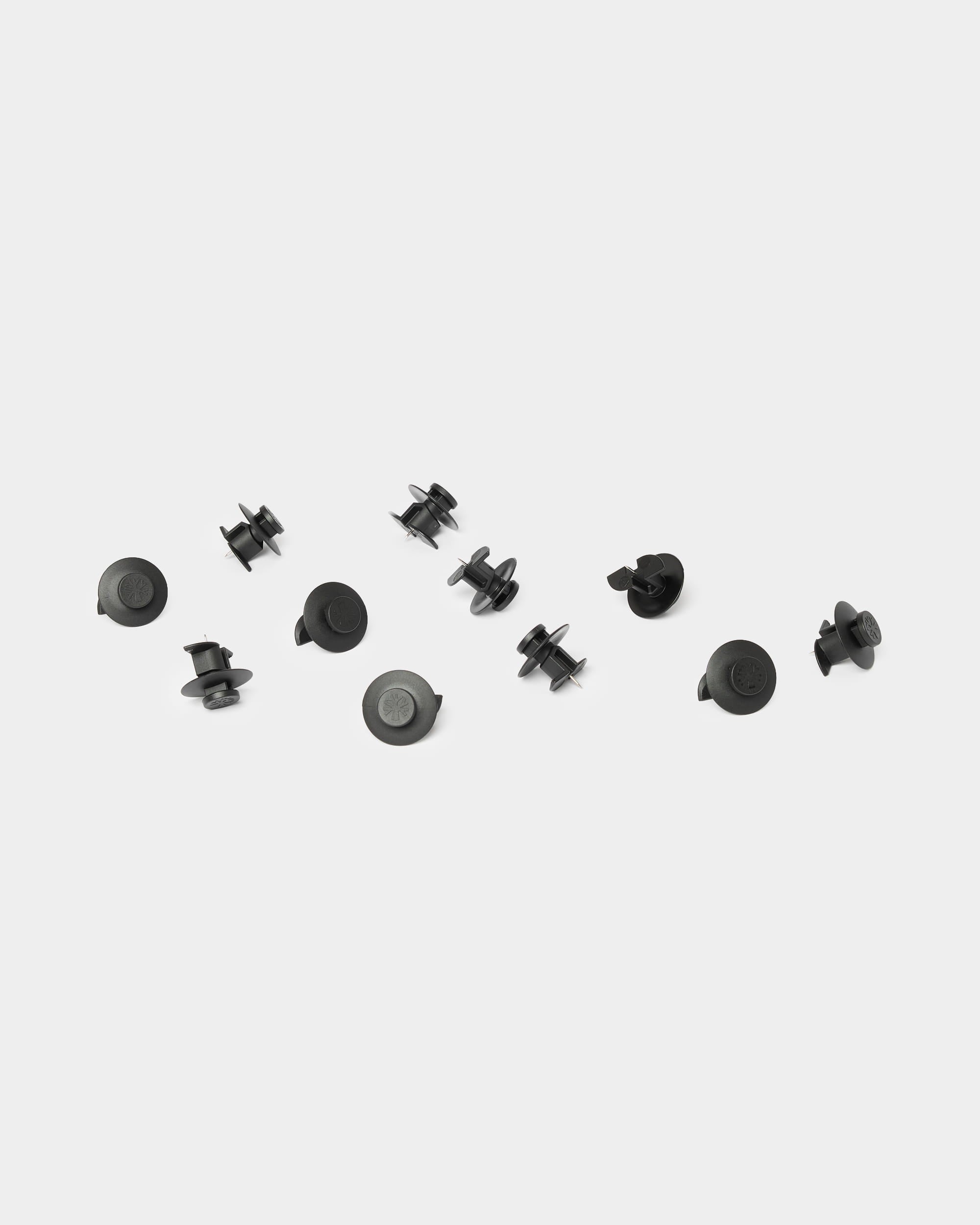 Zehn hellschwarze WoodUpp Dupps-Accessoires sind auf einem schlichten weißen Hintergrund verteilt und wurden für die Verwendung mit Akupanel-Akustikholzpaneelen entworfen.